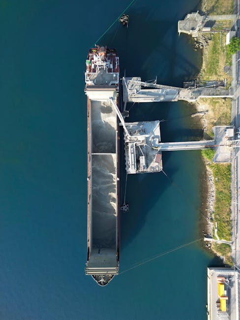Aerial shot of a cargo ship loading at a port in Trieste, Italy, showcasing industrial activity.
